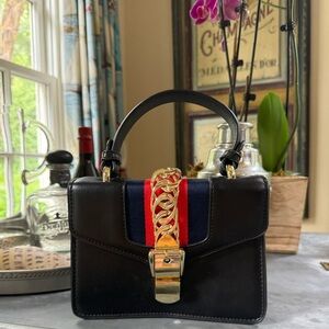 Black purse with navy and red stripe and gold hardware